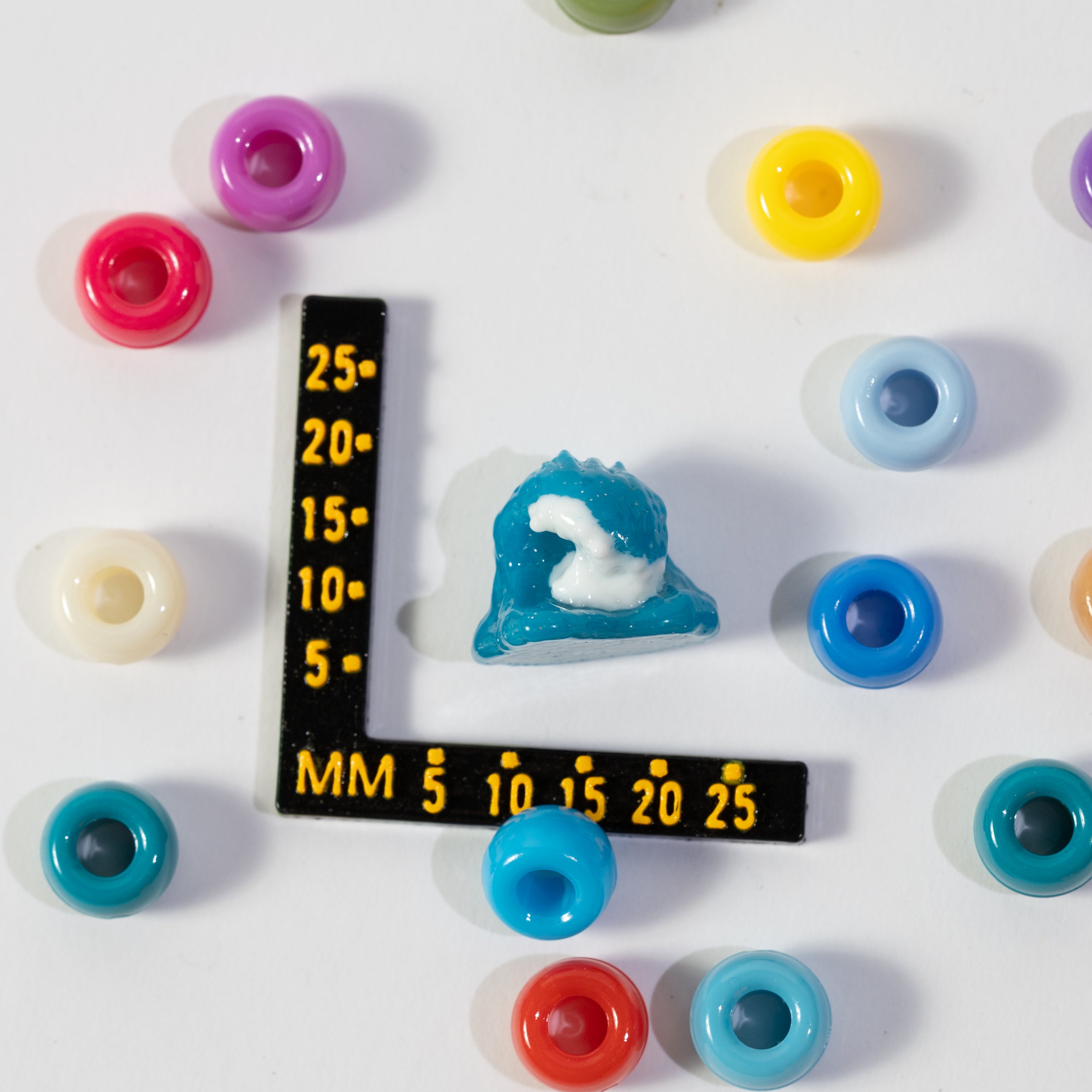 Size guide: a wave kandi bead beside a millimeter ruler for scale