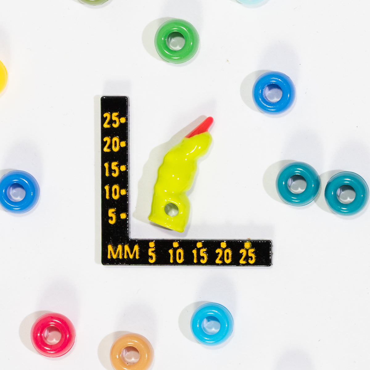 Size guide: a witch finger kandi bead beside a millimeter ruler for scale