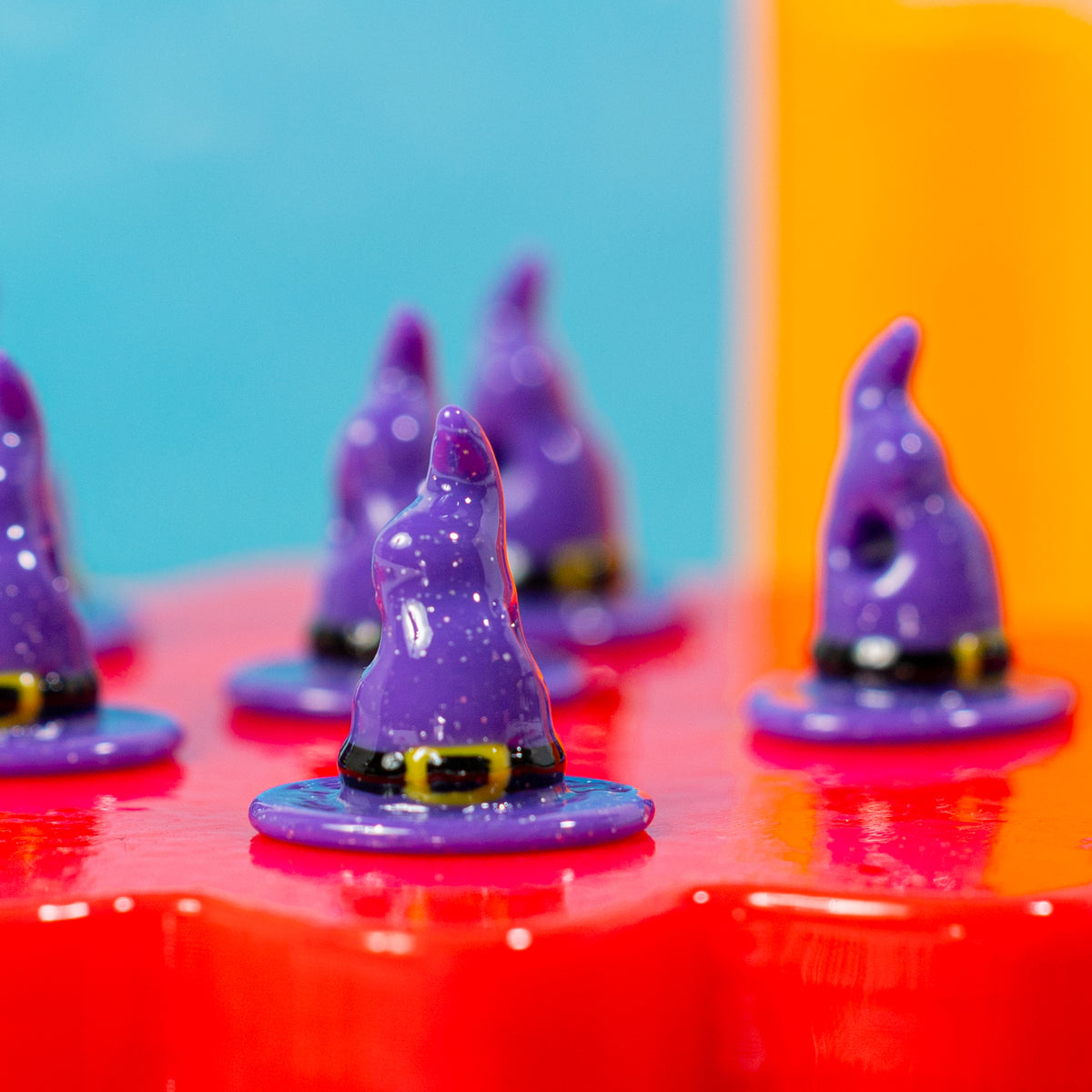 Close-up of purple witch hat kandi beads with black bands and gold buckles on a red riser