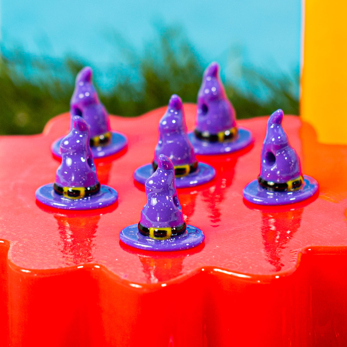 Sparkly purple witch hat kandi beads grouped on a red riser