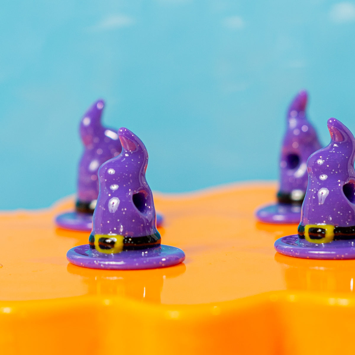 Purple witch hat kandi beads on an orange riser, drilled holes visible