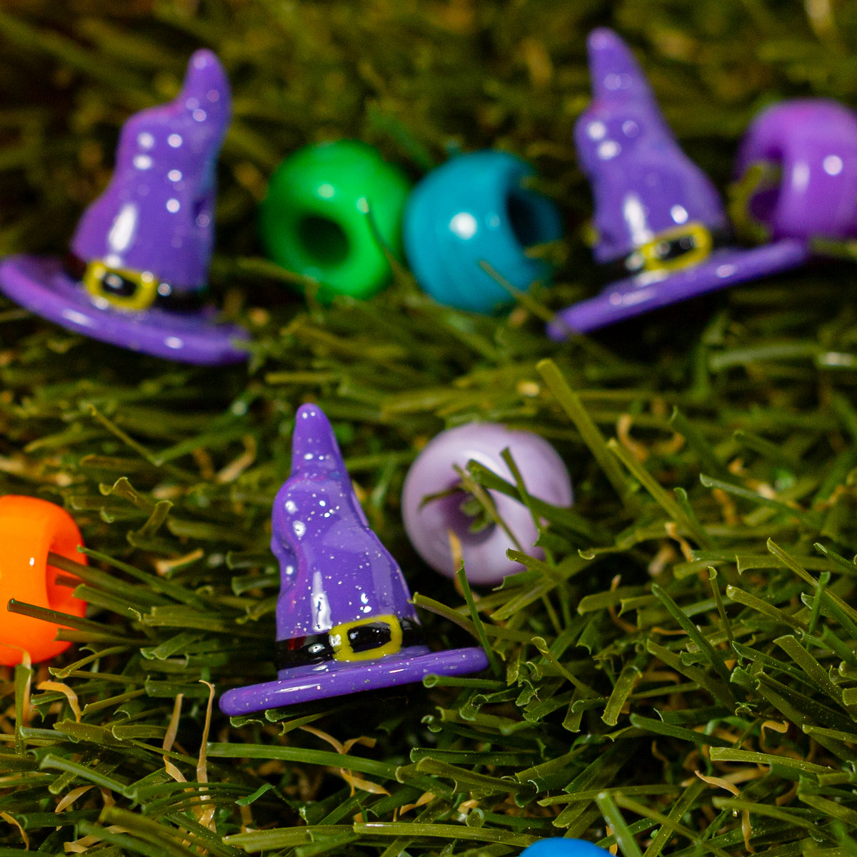 Witch hat kandi beads in green grass beside colorful beads