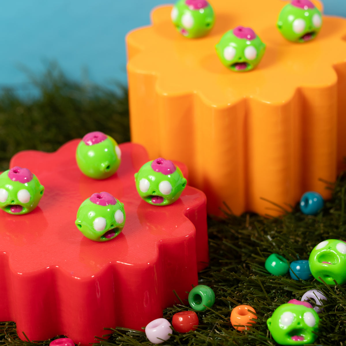 Zombie head kandi beads spread across red and orange risers and green grass